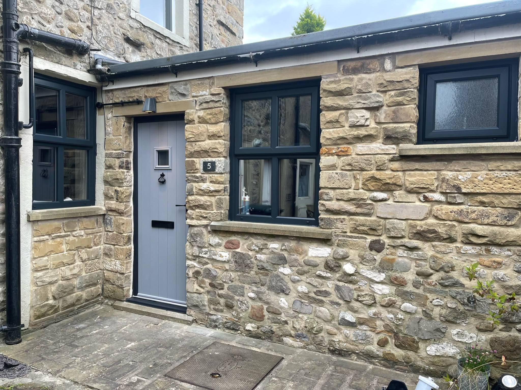 A stone cottage with grey sprayed door and anthracite window frames