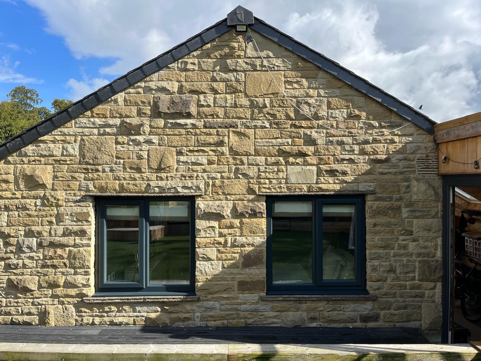 A stone gable with its window frames sprayed anthracite
