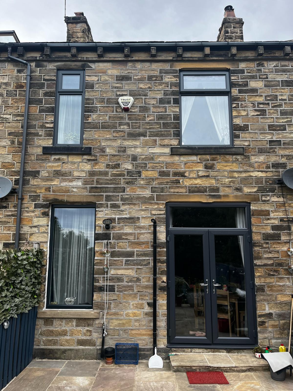 A stone terrace with anthracite sprayed frames and French doors