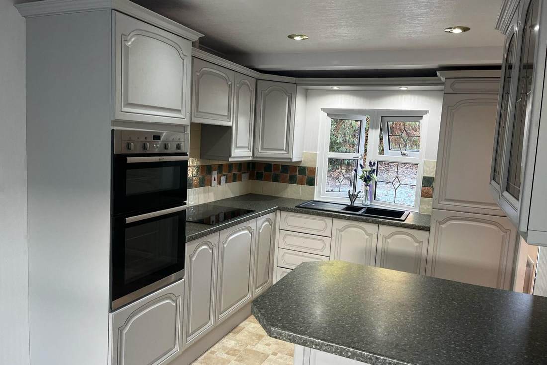 A traditional kitchen resprayed in cream beneath a dark worktop