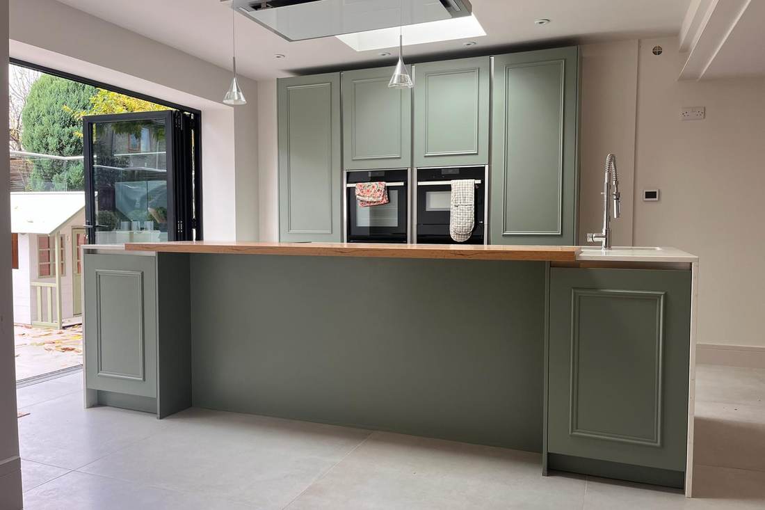 A kitchen island resprayed in sage green, with its oak worktop unchanged