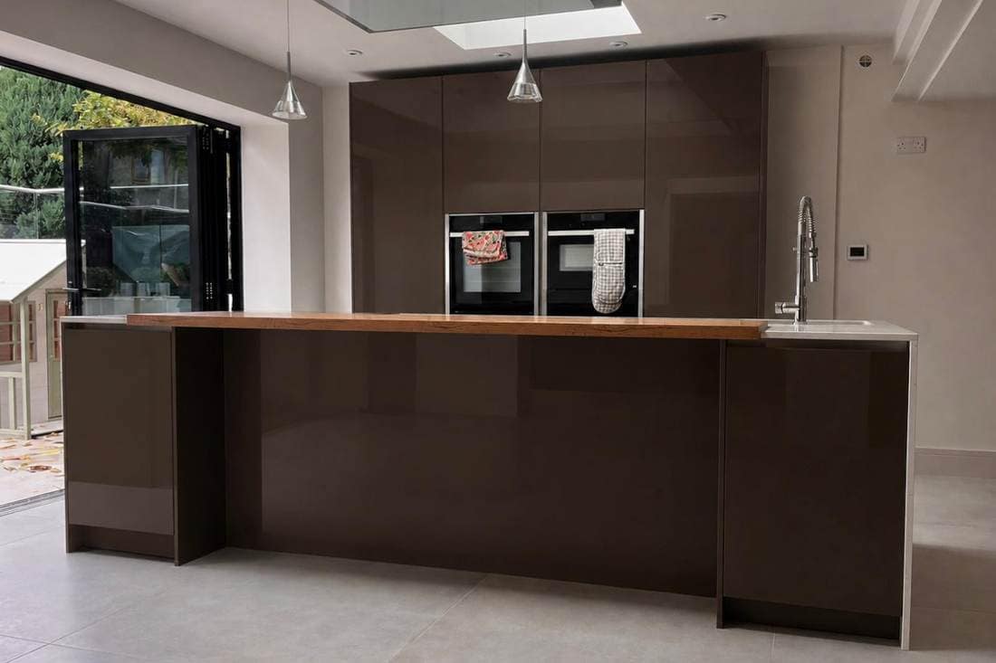 Kitchen island before respraying, in a dark brown gloss, below a skylight and beside bifold doors