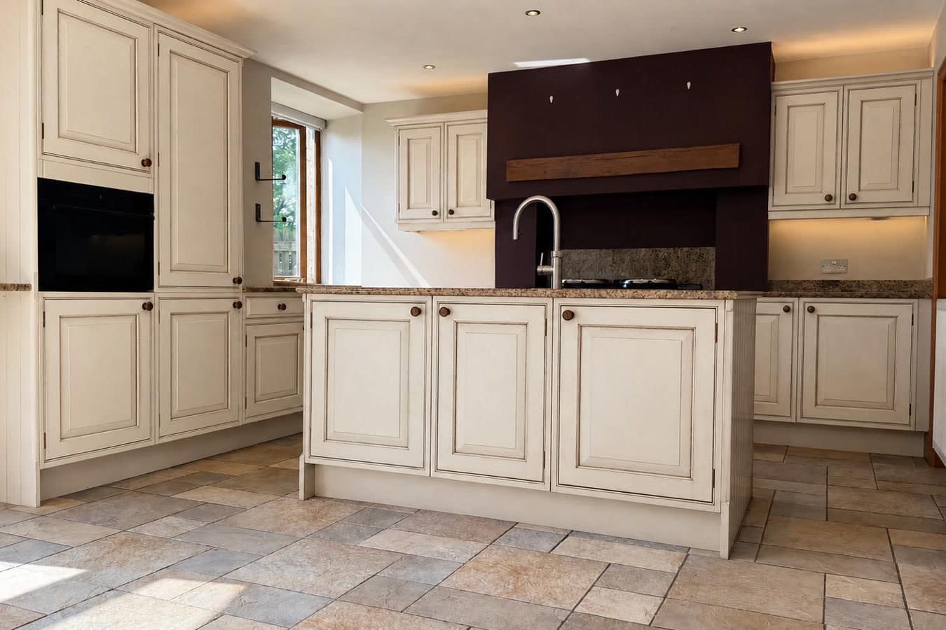 Kitchen before respraying, with the island in cream to match the surrounding units, on a tiled floor