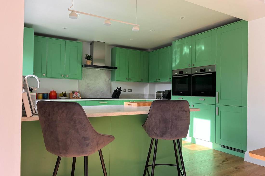 A kitchen resprayed in a bright green, with bar stools at the island