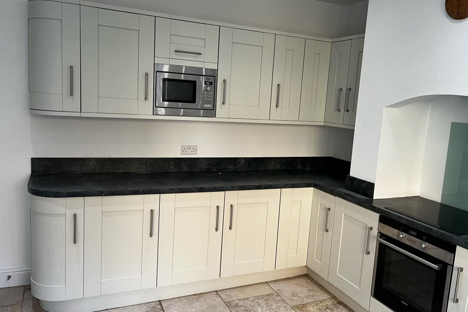 The same kitchen after respraying, with every door and the curved end unit in a soft cream