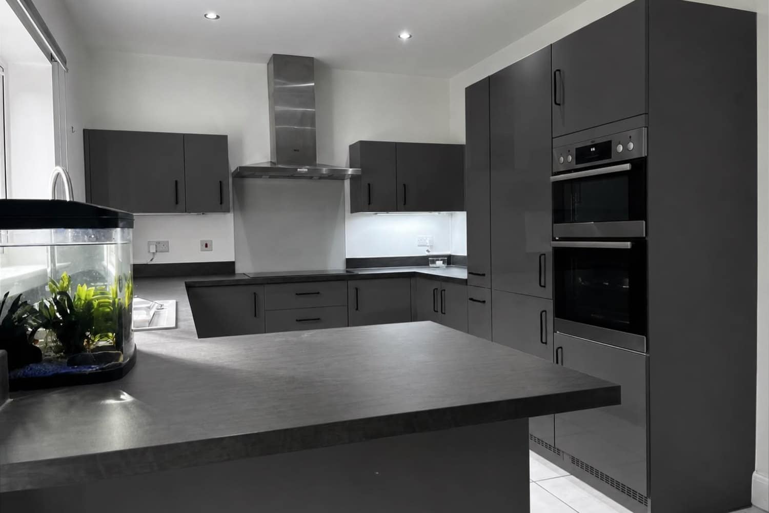 The same kitchen after respraying in a deep graphite, with the island and tall units matched
