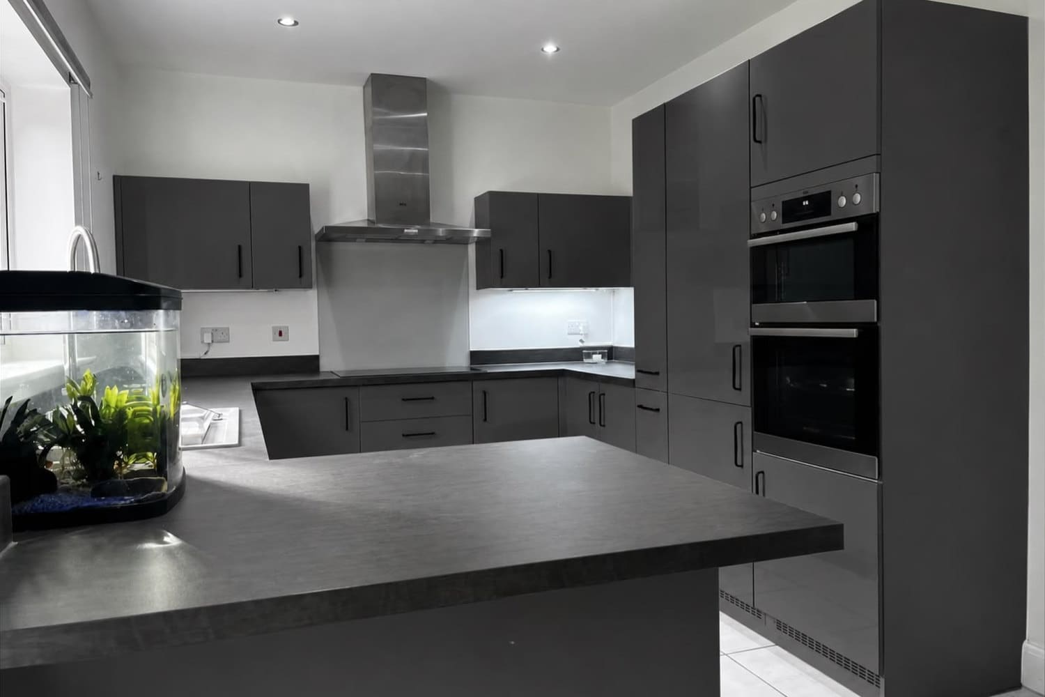 A handleless kitchen resprayed in a deep graphite, with an island and twin ovens
