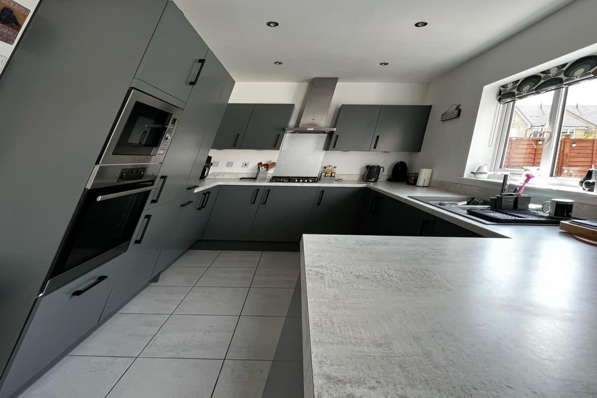 A slab-door kitchen resprayed in a matt graphite, with new black bar handles