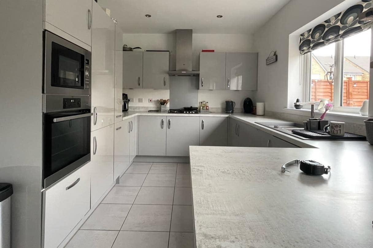 A slab-door kitchen before respraying, in a high-gloss white with chrome handles