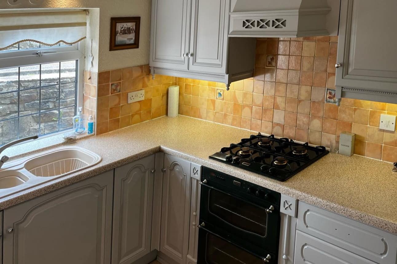 The same kitchen after respraying in a pale grey, canopy included, with the original tiles kept
