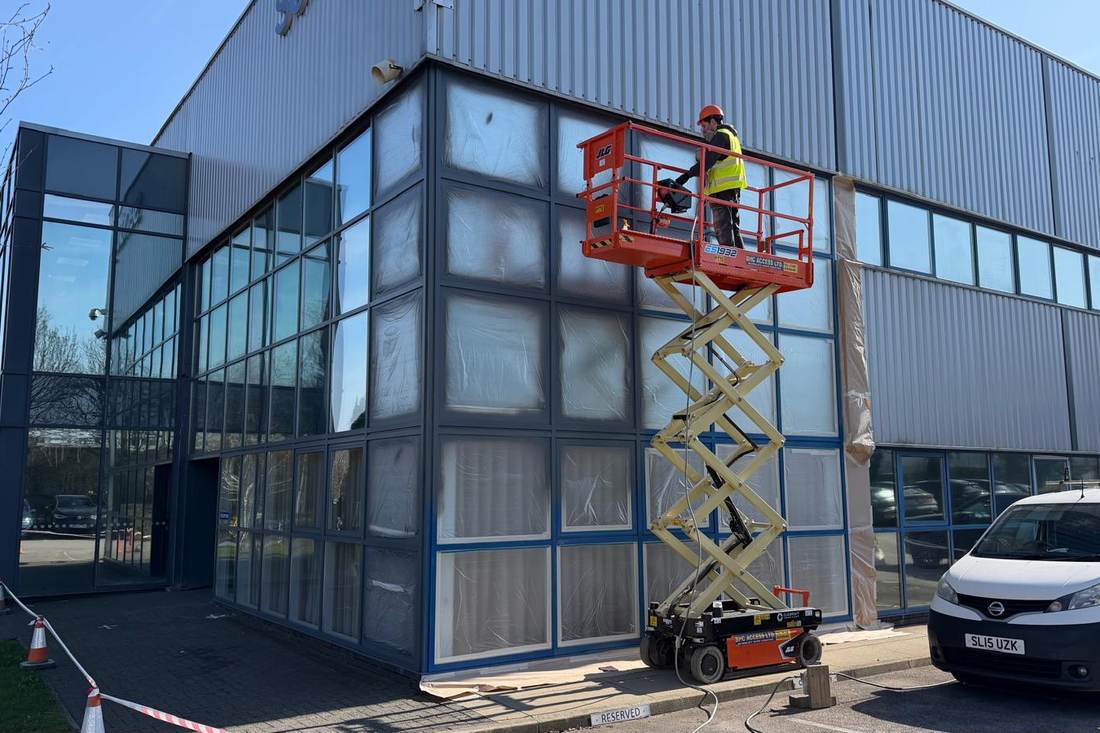 Commercial curtain-wall glazing being sprayed from a scissor lift