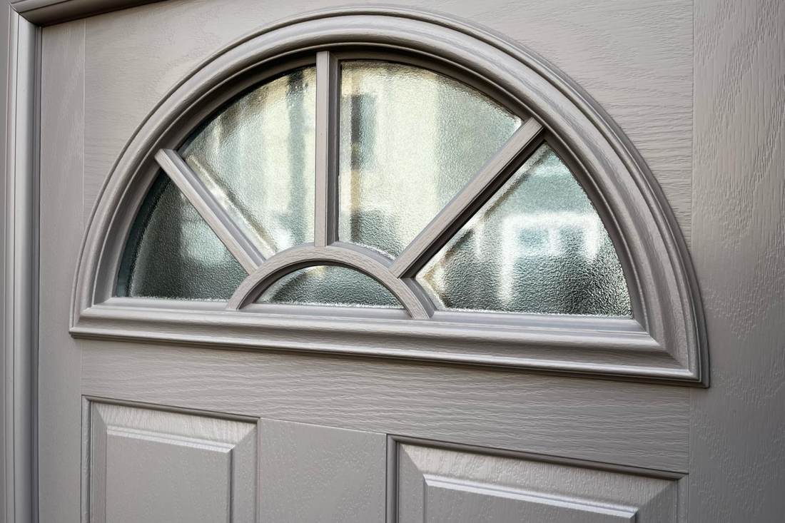 Close up of the same grey door's arched fanlight and panel detail