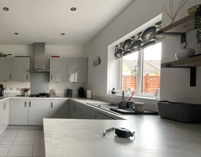 Modern handleless kitchen before respraying, with pale grey gloss doors and a light stone worktop