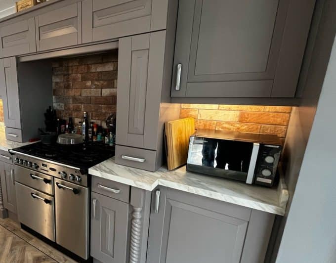 The same galley kitchen after respraying, with the oak doors resprayed in a deep warm grey
