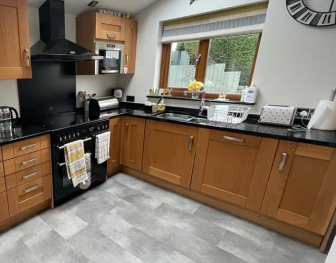U-shaped kitchen before respraying, with orange-toned oak doors and black granite worktops