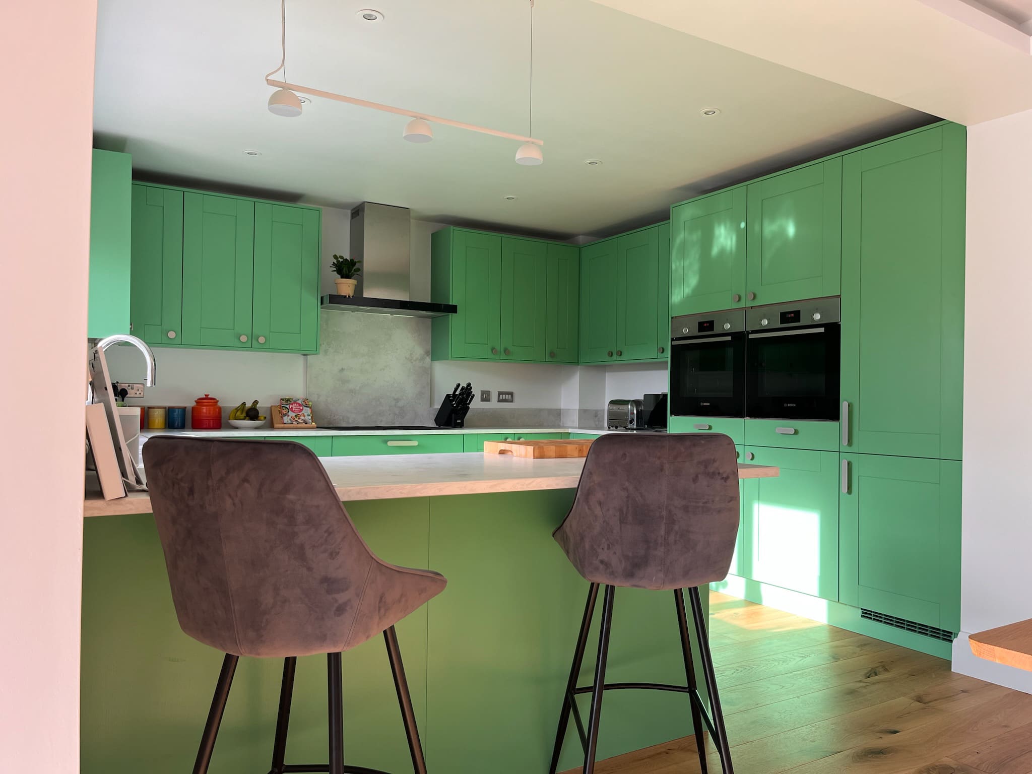 Bright green kitchen respray with island and bar stools