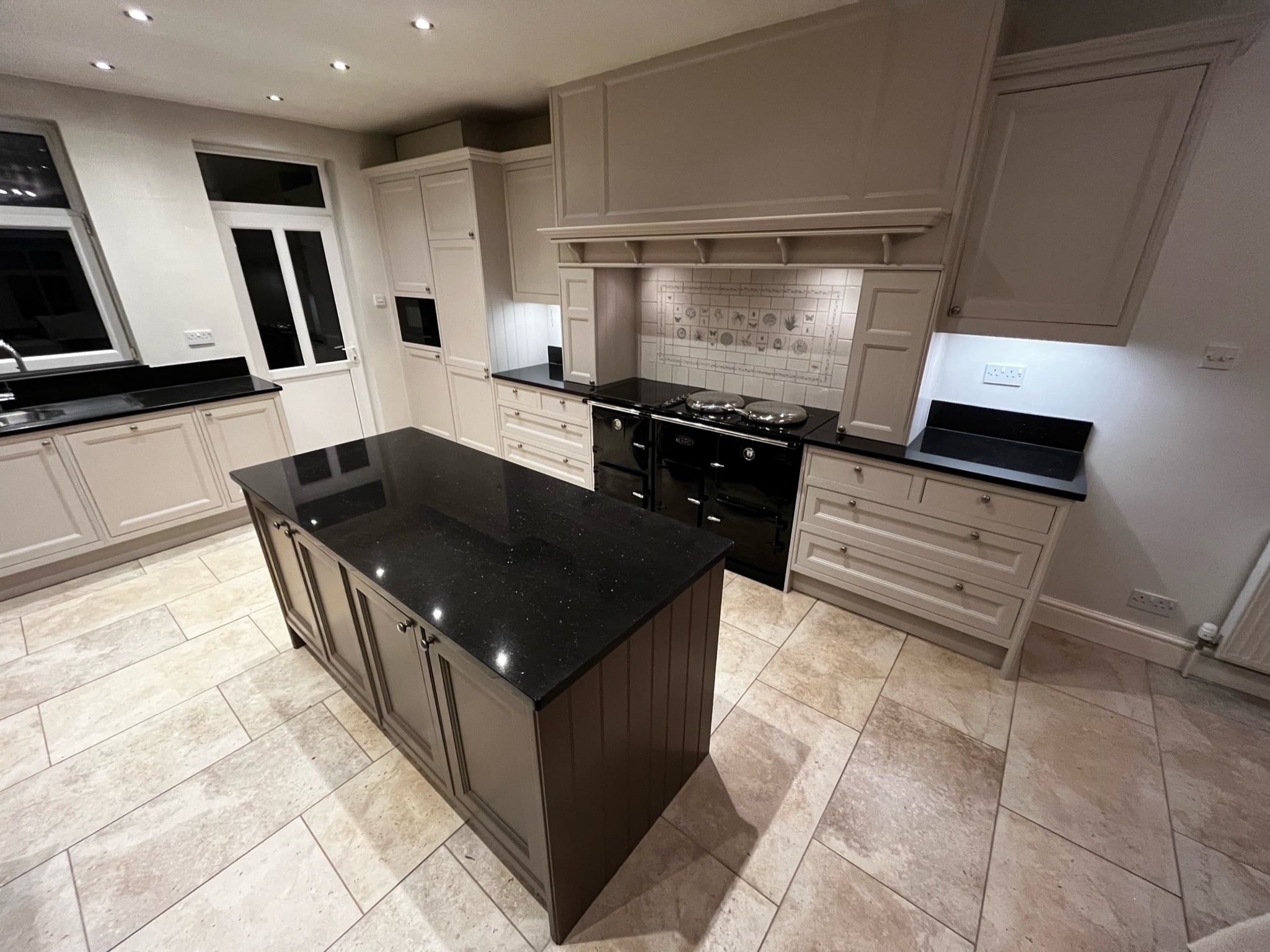 Taupe kitchen after respraying, with a black granite island